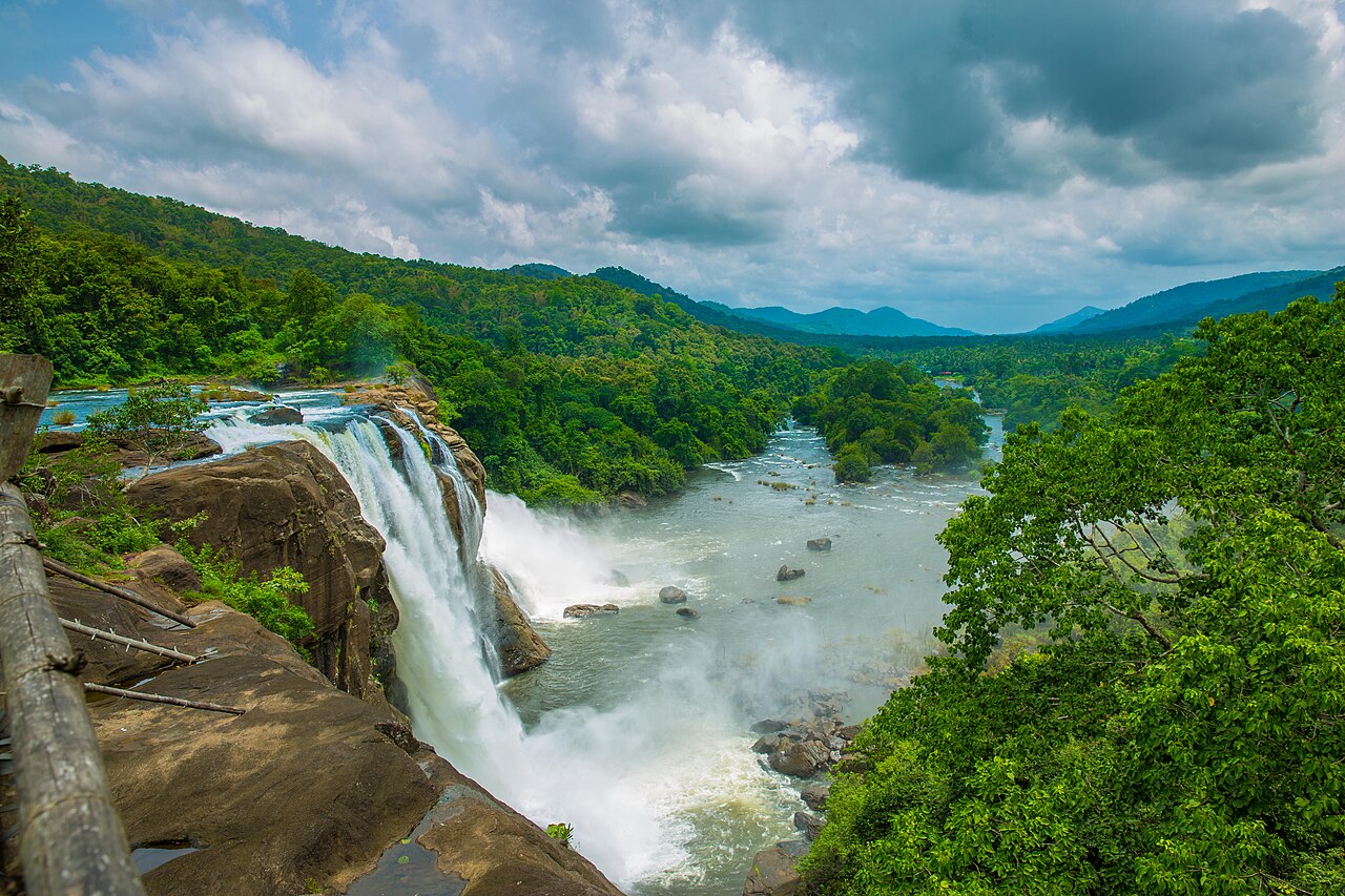 Athirappilly Falls on the Chalakudy river during the monsoon, water flowing across a wide rock shelf.